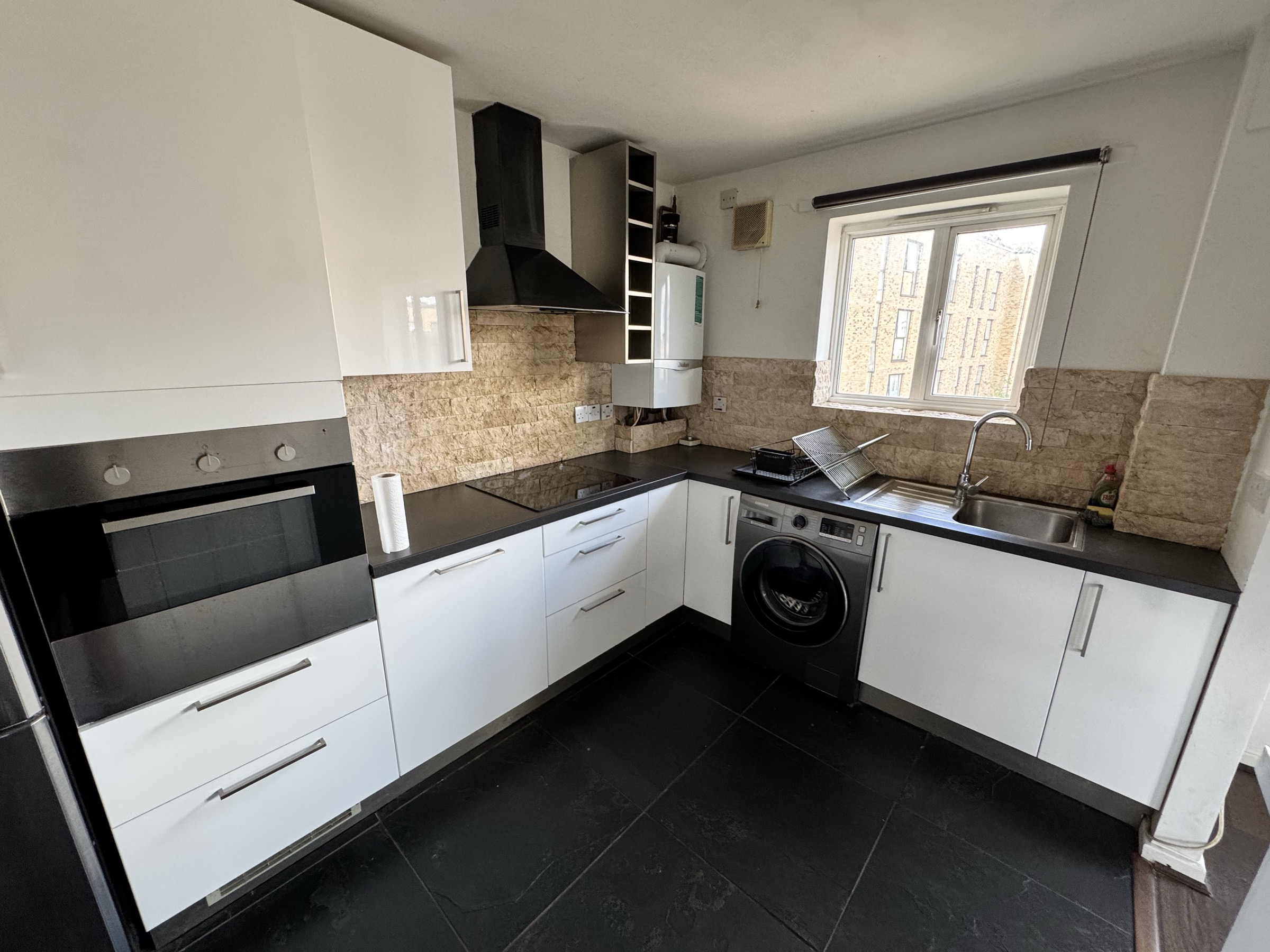 Modern fitted kitchen with black worktops and integrated appliances