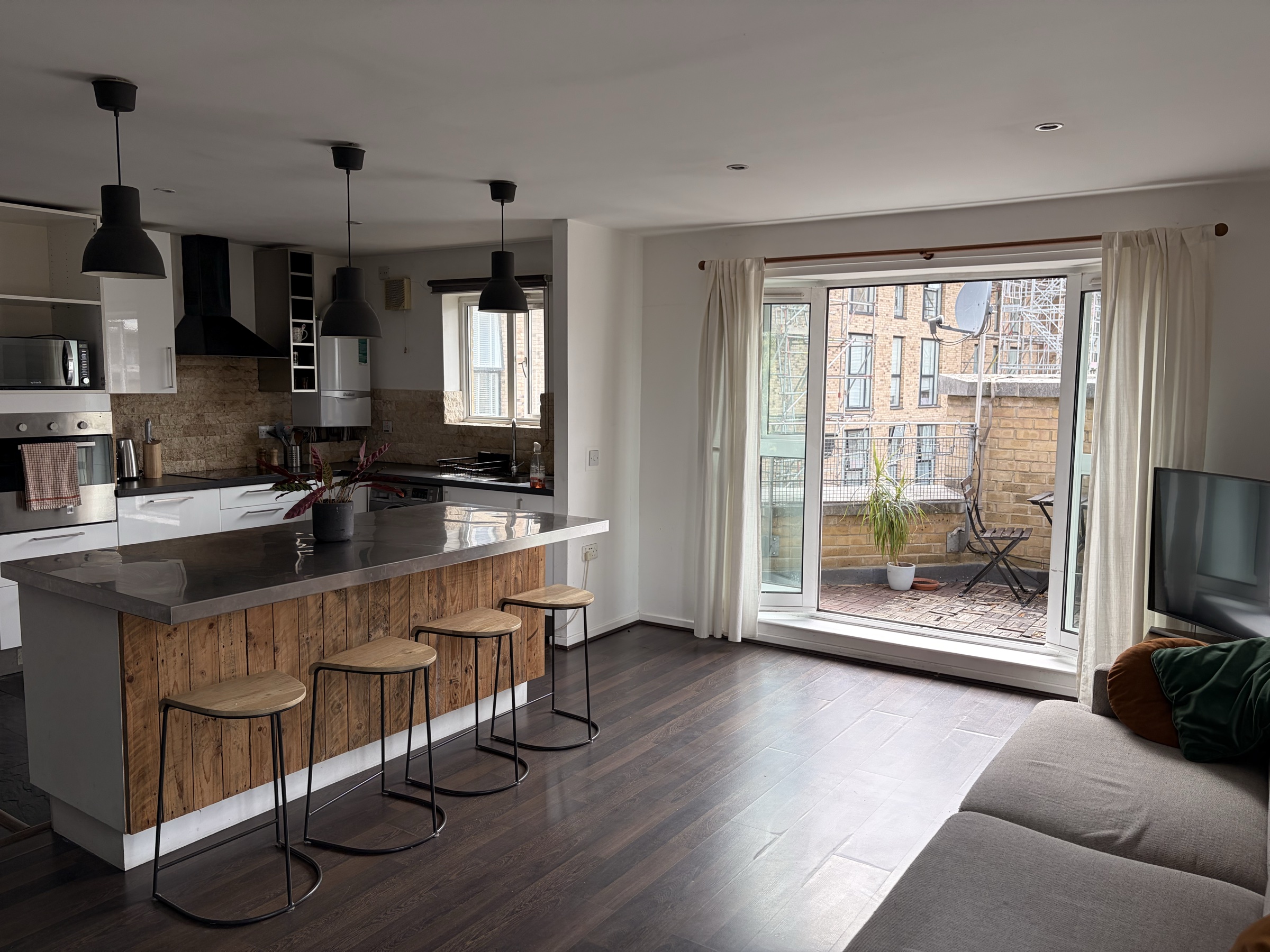 Daylight view across the open-plan kitchen, living room and balcony