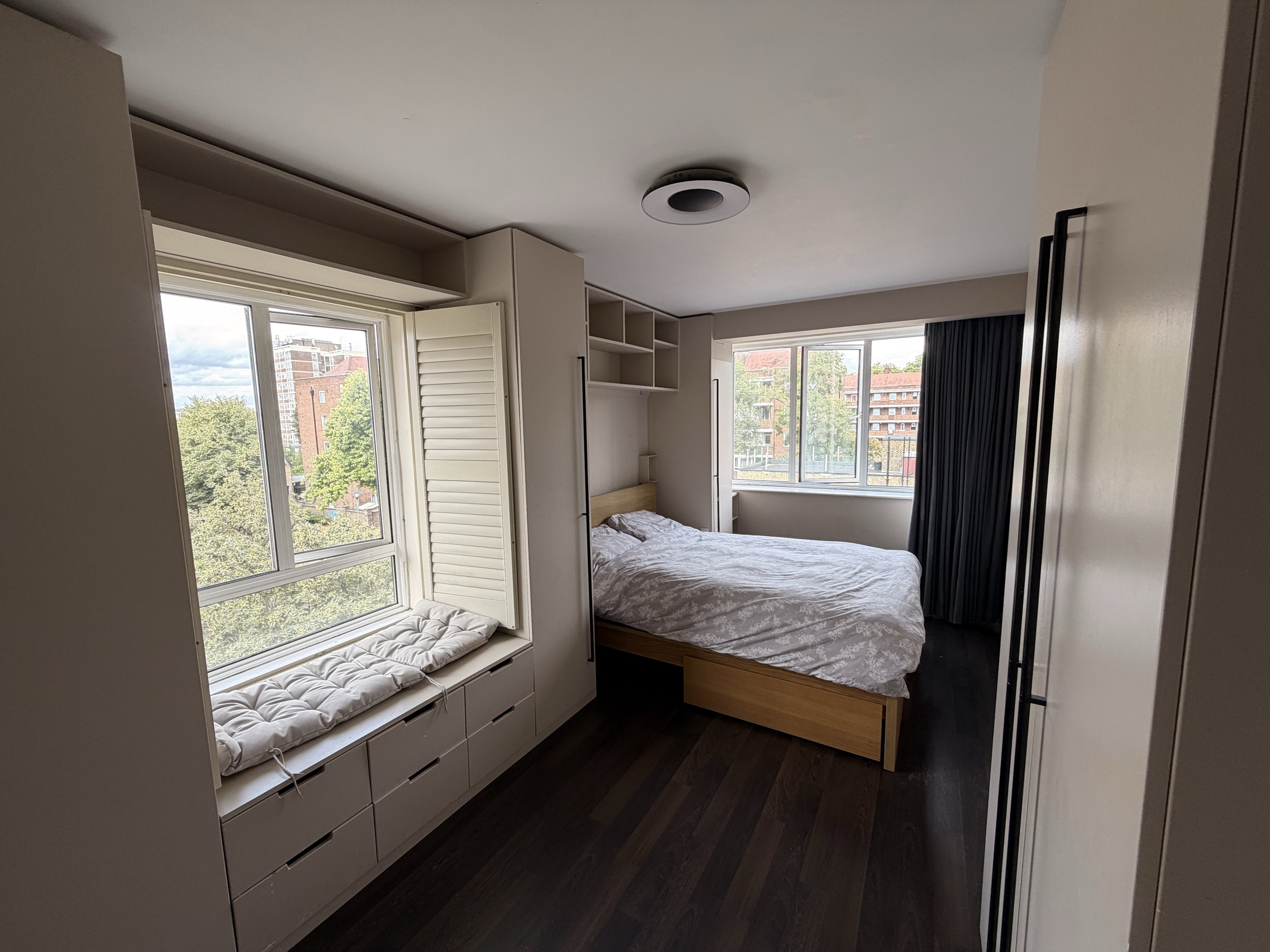 Principal bedroom with built-in wardrobes, shelving and window seating